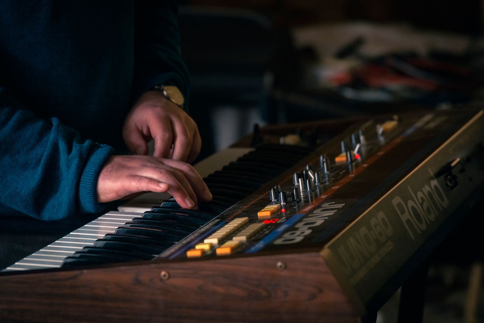 Händer som spelar på en klassisk Roland Juno-60-synthesizer, en symbol för 80-talsmusiken