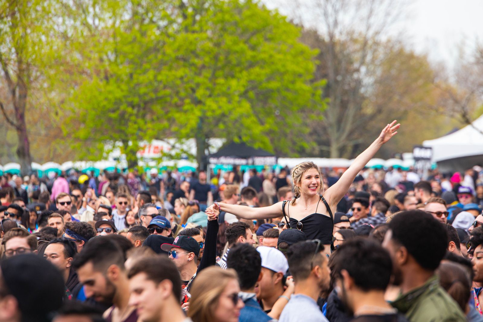Festivalbesökare i sommarkläder framför en scen en solig dag