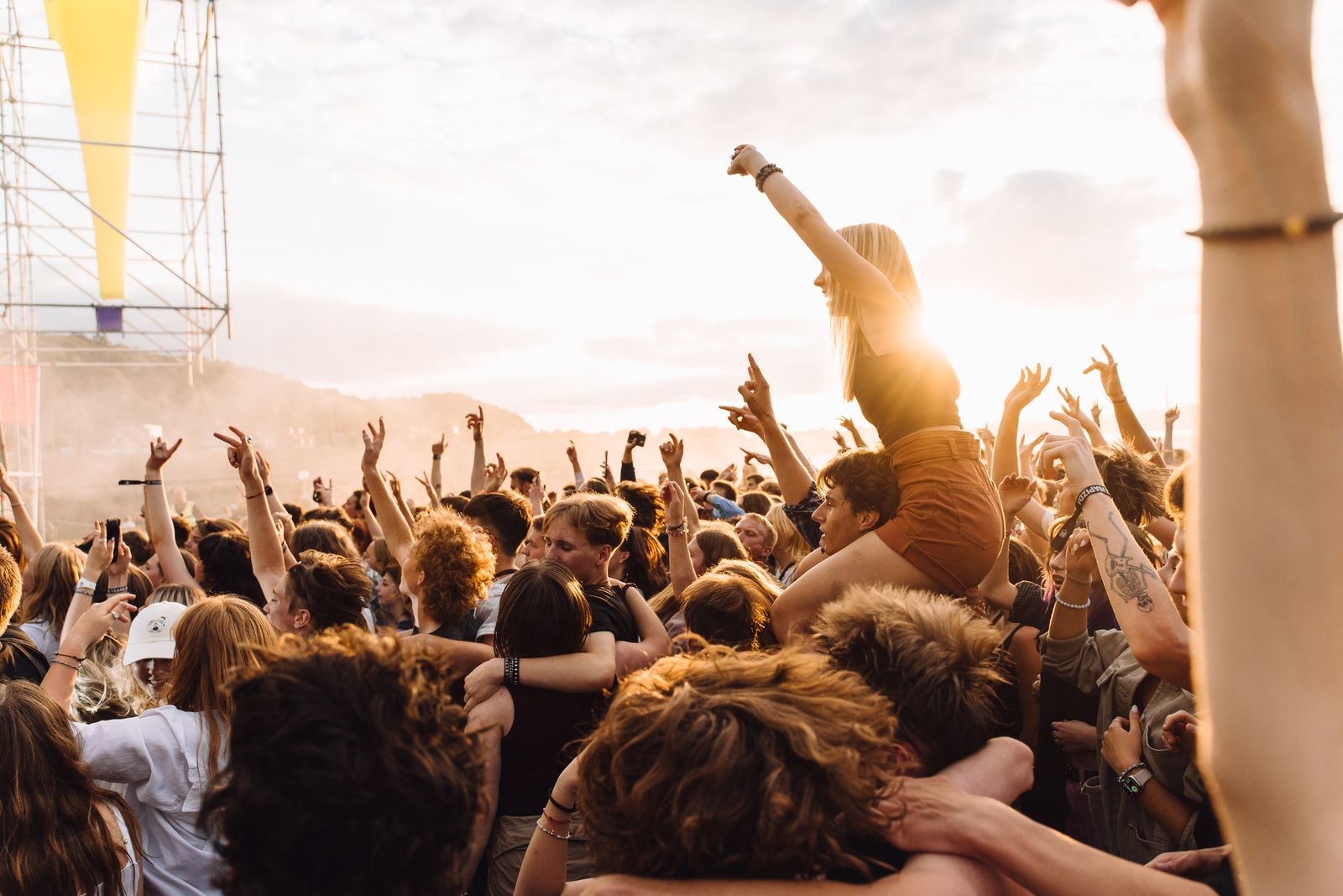 Jublande publik på en utomhuskonsert i sommarsolnedgång – stämningen som Gyllene Tiders musik förknippas med