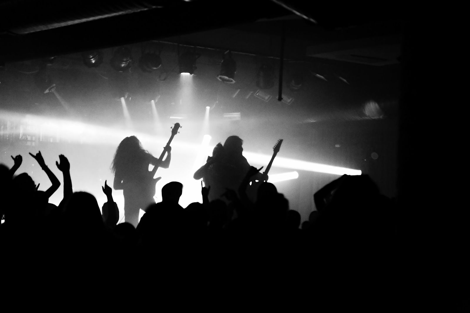 Siluetter av ett rockband på en scen med starkt motljus och publik framför