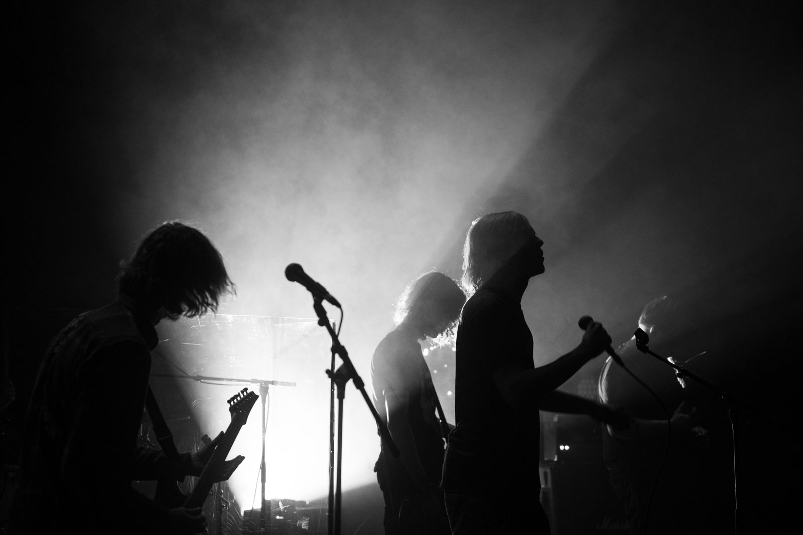 Silhuetter av ett rockband som spelar live i dramatiskt scenljus