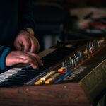 Händer som spelar på en klassisk Roland Juno-60-synthesizer, en symbol för 80-talsmusiken