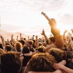 Jublande publik på en utomhuskonsert i sommarsolnedgång – stämningen som Gyllene Tiders musik förknippas med