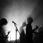 Silhuetter av ett rockband som spelar live i dramatiskt scenljus